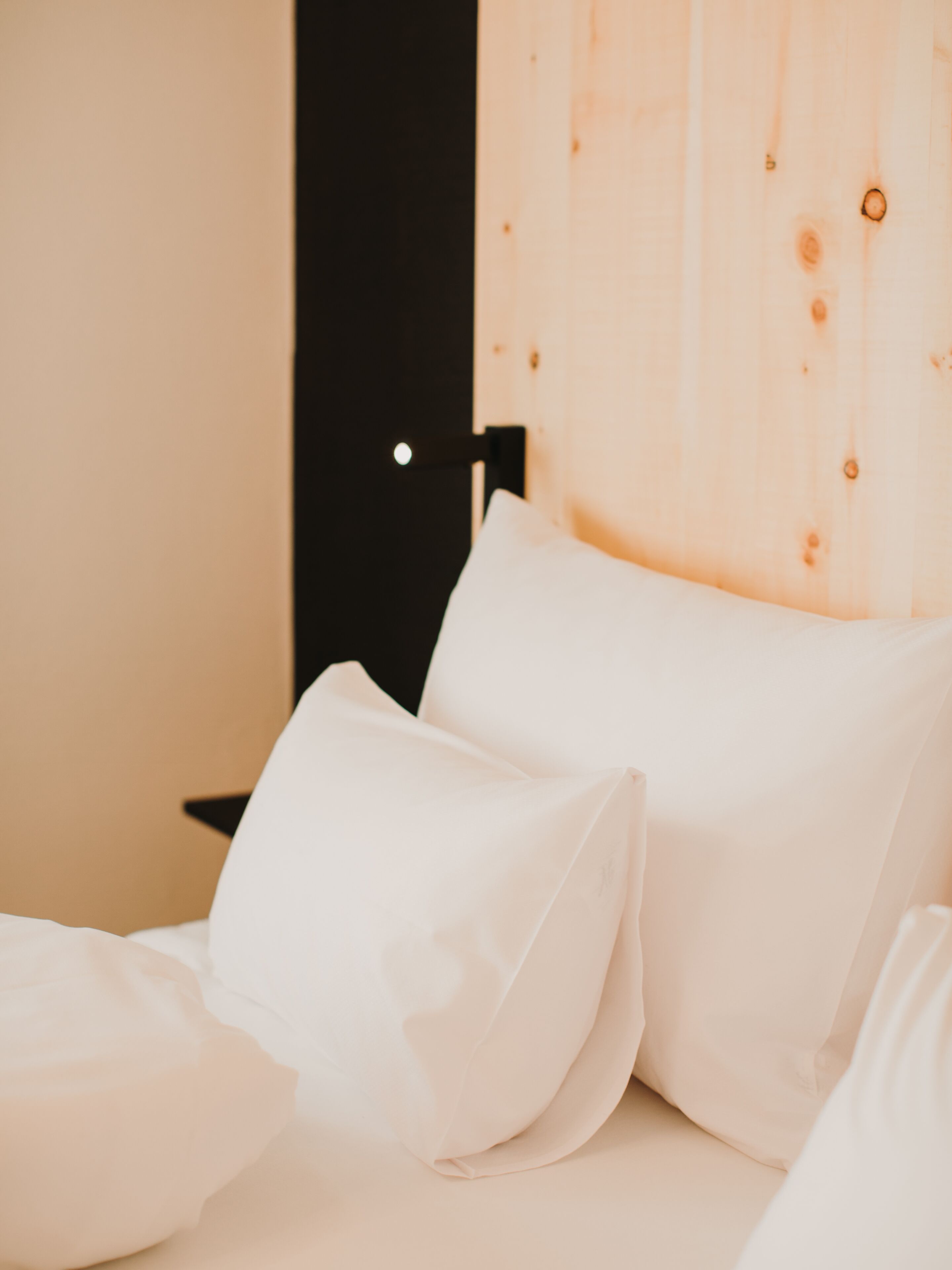 Ein Bett mit weißer Bettwäsche und einem hölzernen Kopfteil.