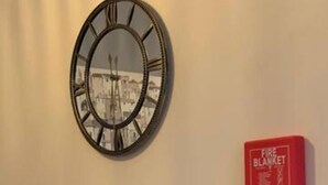A kitchen with a round wall clock, a stainless steel sink, and a red fire blanket on the wall. - Sherwood-free Parking-business-leisure (Nottingham)