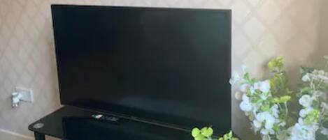 Sala de estar con mueble multimedia negro, televisor de pantalla plana y estante decorativo con la palabra 'HOME'.