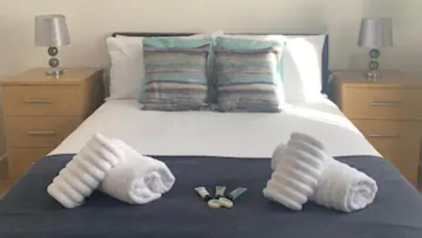 A neatly made bed with two towels and a set of toiletries on the bed. There is a painting on the wall above the bed. - Sherwood-free Parking-business-leisure (Nottingham)