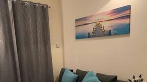 A living room with a dark sofa, a blue rug, and a painting on the wall. - Sherwood-free Parking-business-leisure (Nottingham)
