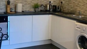 A modern kitchen with a built-in washing machine, a coffee maker, and a wall-mounted clock. - Sherwood-free Parking-business-leisure (Nottingham)