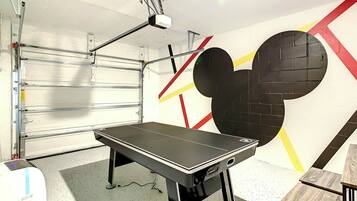 A room with a table, a projector mounted on the ceiling, and a wall with a large Mickey Mouse design.