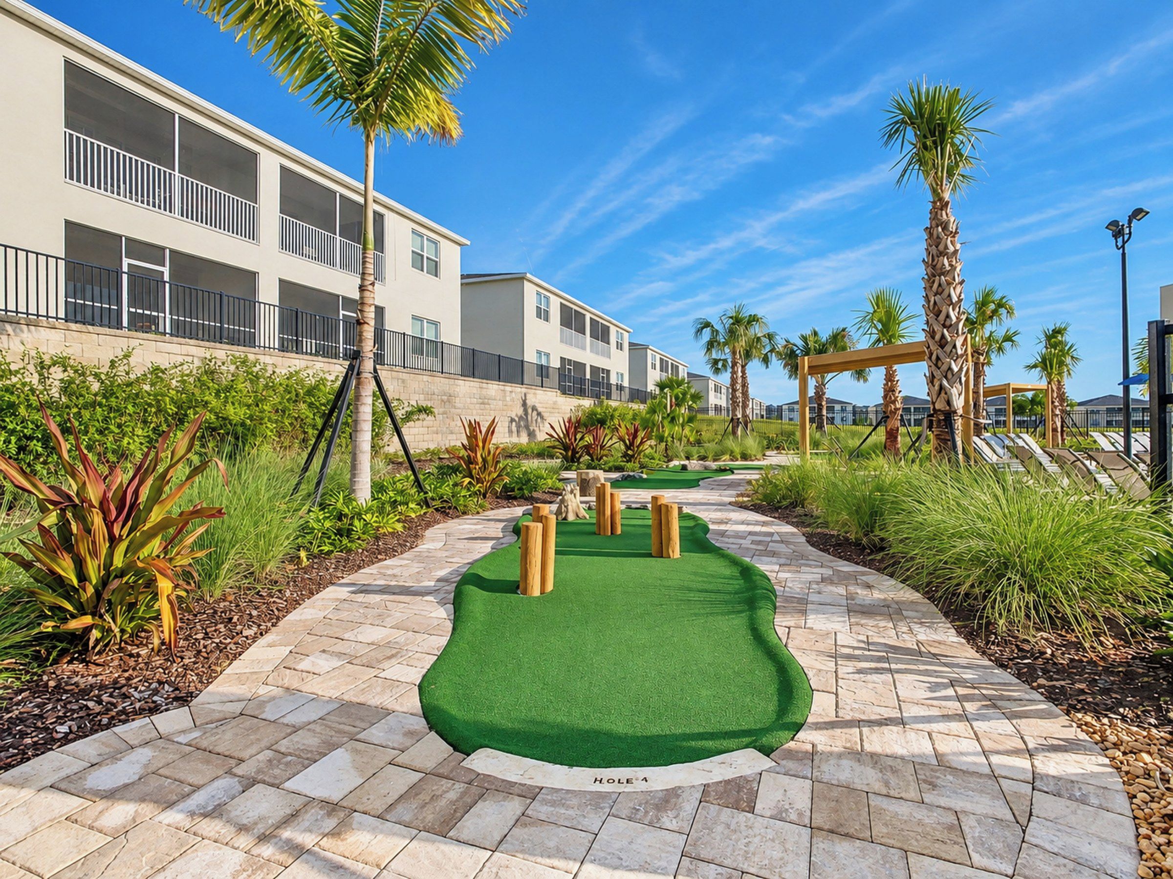 Um campo de mini golfe com gramado verde, obstáculos de madeira e um caminho.