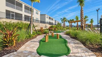 Um campo de mini golfe com gramado verde, obstáculos de madeira e um caminho.