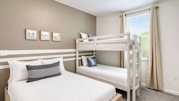 Quarto com cama beliche, uma cama de solteiro e janela com cortinas.