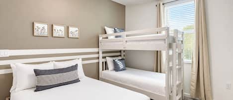 Une chambre avec un lit superposé, un lit simple et une fenêtre avec des rideaux.