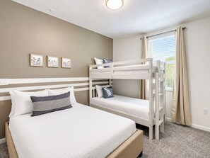 Un dormitorio con literas, una cama individual y una ventana con cortinas.