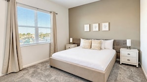 A bedroom with a bed, two bedside tables, a ceiling fan, and a window with curtains.