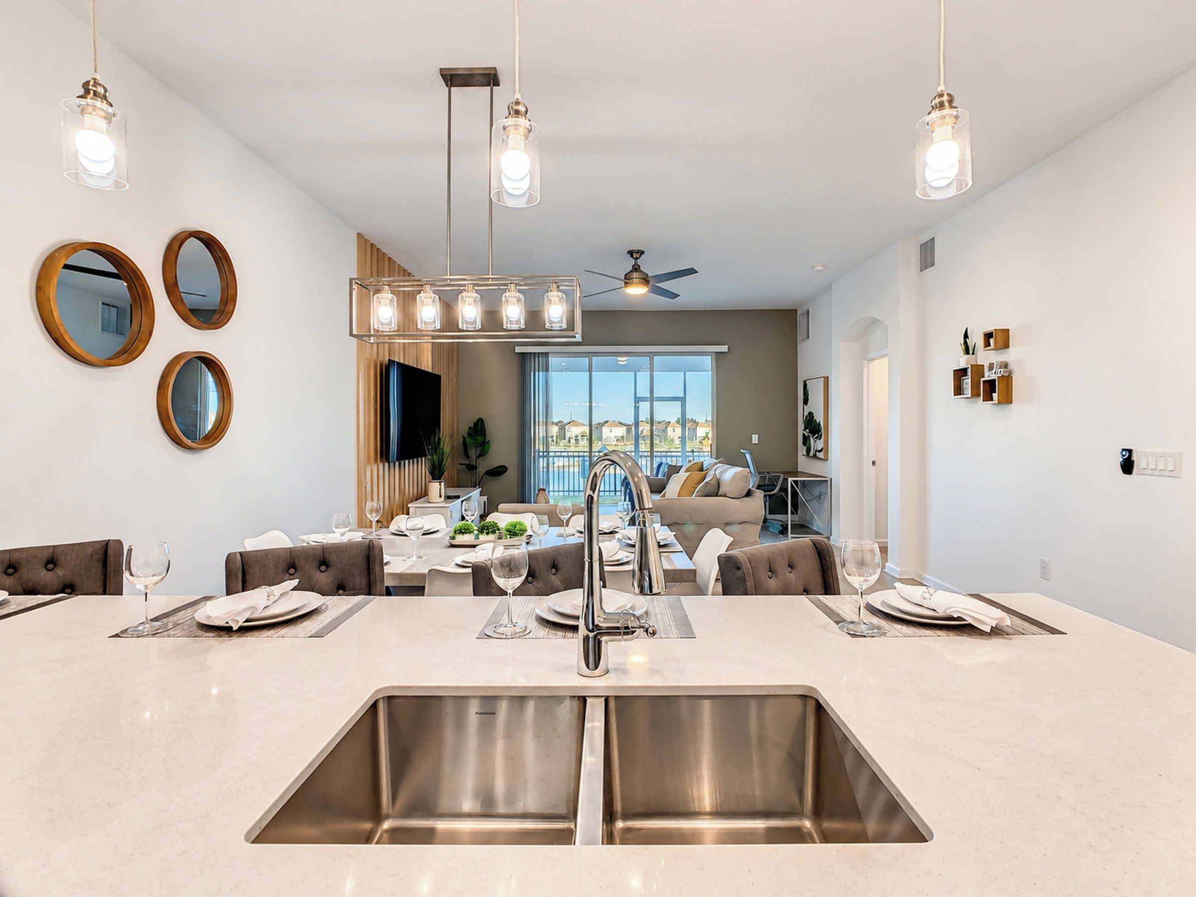 Een moderne keuken met een centraal eiland, roestvrijstalen spoelbakken en hanglampen.