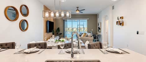 Une cuisine moderne dotée d’un îlot central, d’éviers en acier inoxydable et de luminaires suspendus.