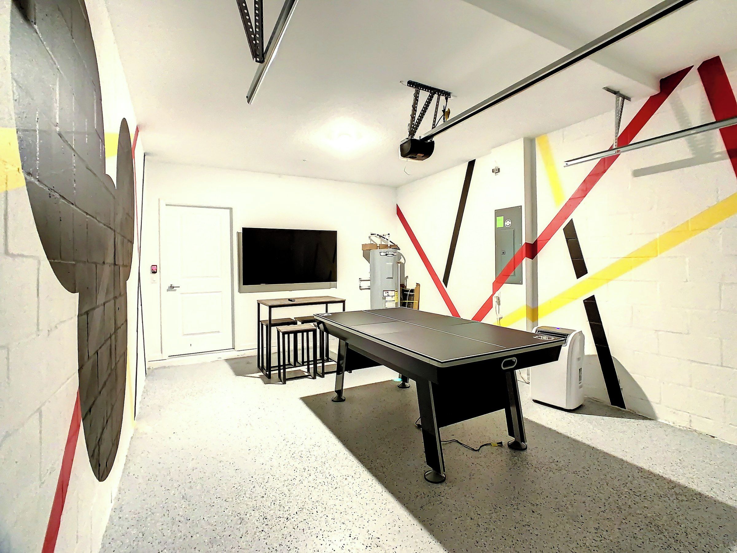 A billiards table in a room with a white wall, a television, and a door.