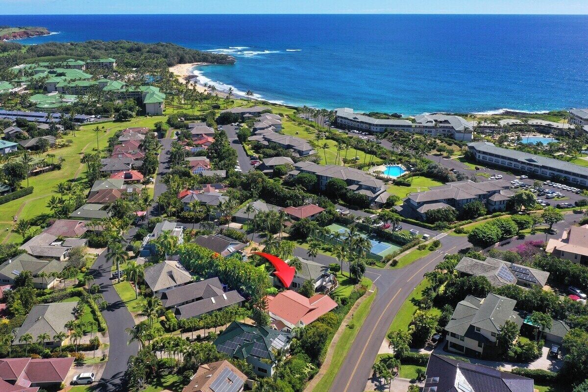 Vista aérea de una zona residencial costera con casas, calles y una playa.
