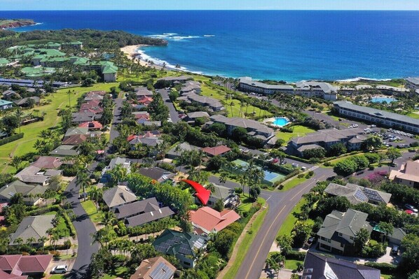 An aerial view of a coastal residential area with houses, roads, and a beach.