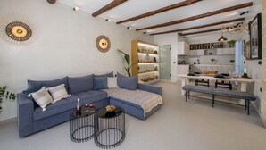 Una sala de estar moderna con un sofá azul, una mesa de centro y una zona de comedor con un banco.