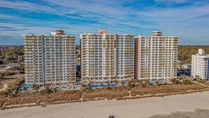 Un hôtel de grande hauteur, avec de nombreux étages, une vue sur la plage et un espace piscine.