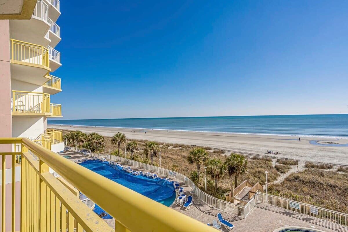 A balcony with a view of a beach and a pool.