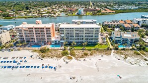 A hotel with multiple floors, a pool, and a beach area with sun loungers. - SandCastle 1804 - Beautiful updates, Breathtaking view, tons of amenities (Indian Shores)