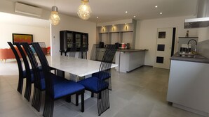 A modern kitchen with a central island, black chairs with blue cushions, and pendant lighting. - Domaine des Bois Argentés (Pruniers-en-Sologne)