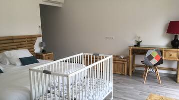 Una habitación infantil con una cuna, una cama, un escritorio y una silla.