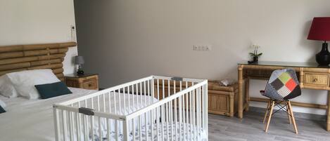 A baby room with a crib, a bed, a desk, and a chair.