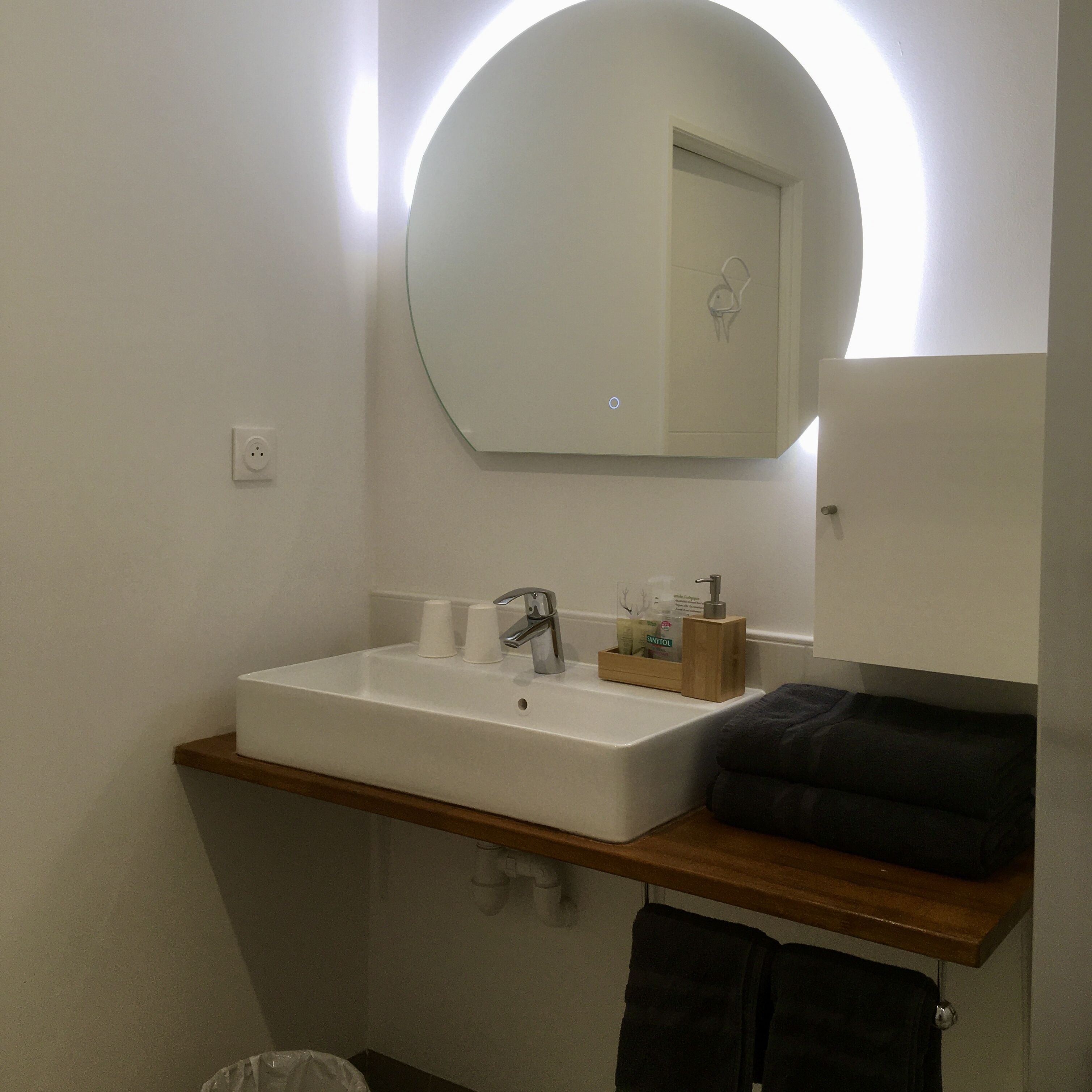 A bathroom with a white sink, a mirror, and a towel rack.
