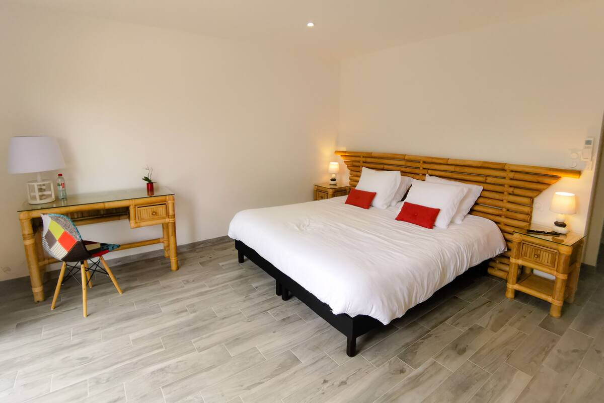A neatly arranged bedroom with a bed, bedside tables, a desk, and a chair.