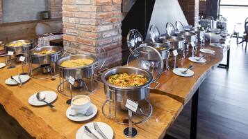 A buffet setup with various food stations, a brick wall, and a large window.