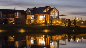 A large, modern house with multiple windows and a reflection in the water. - Cerro Azul Hotel Fazenda (Capao Alto)
