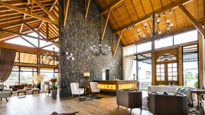 A spacious lobby with a high wooden ceiling, stone walls, and a large leather rug. - Cerro Azul Hotel Fazenda (Capao Alto)