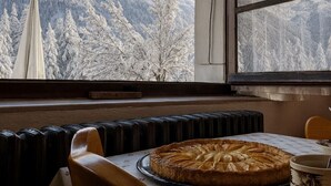 A pie on a tray by a window with a view of snow-covered mountains.