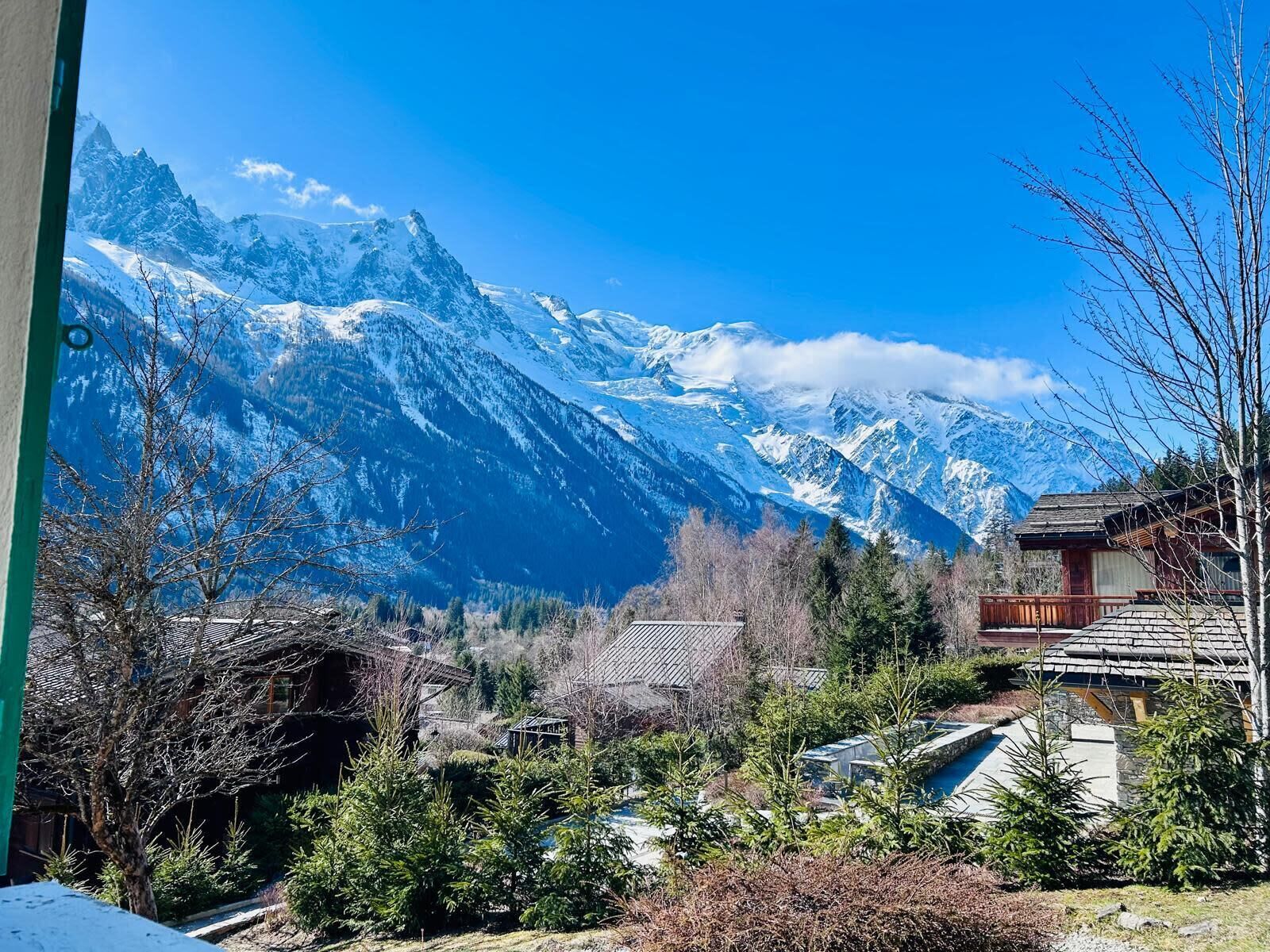 A mountain view with snow-capped peaks, a wooden cabin, and a pool area.