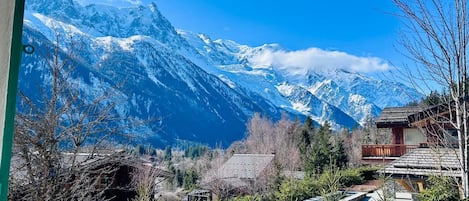 A mountain view with snow-capped peaks, a wooden cabin, and a pool area.