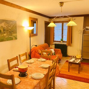 En spiseplads med et bord til fire personer, en sofa og en radiator.