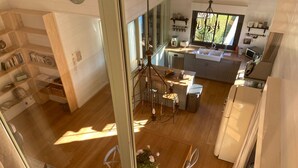 A modern kitchen with a large window, wooden flooring, and a dining area with a table and chairs. - Sumptuous Cap Ferret Style House (La Teste-de-Buch)