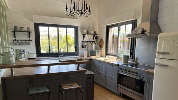 A modern kitchen with a central island, bar stools, a built-in oven, and a refrigerator. - Sumptuous Cap Ferret Style House (La Teste-de-Buch)