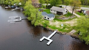 Een pand aan de rivier met een aanlegsteiger, een huis en een bootje.