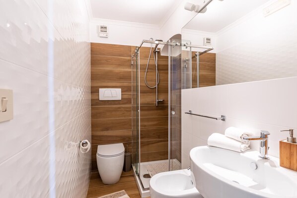 Een moderne badkamer met een douchecabine van glas, een toilet en een wastafel met een handdoek.