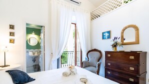 A hotel room with a bed, a dresser, a chair, a mirror, and a window with curtains. - Stefania Flat- Amalfi centre (Amalfi)