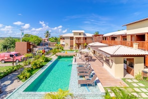 A resort with a swimming pool, lounge chairs, and a view of the surrounding landscape.