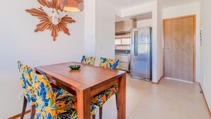 Un coin repas avec une table et des chaises en bois, un élément décoratif mural et une cuisine en arrière-plan.