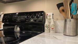 A kitchen with a black stove, a white countertop, and two kitchen bottles with labels. - Classic City 3 bed 2 bath condo with deck close to Five Points & UGA in Athens (Athens)