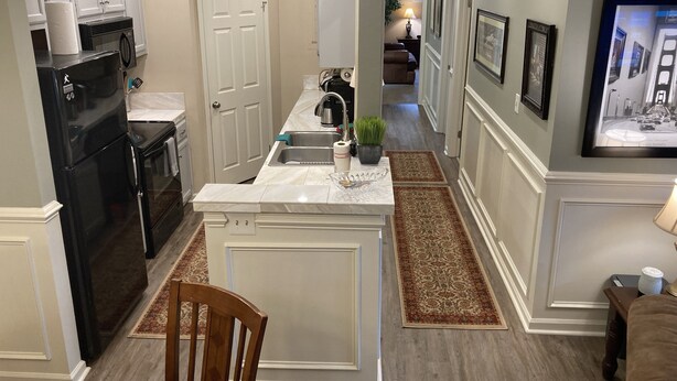 A modern kitchen with white cabinetry, a black refrigerator, and a central island with a sink. - Classic City 3 bed 2 bath condo with deck close to Five Points & UGA in Athens (Athens)