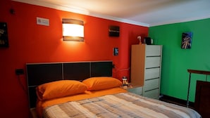 Uma cama com um cobertor listrado, cabeceira de madeira e almofadas laranja.
