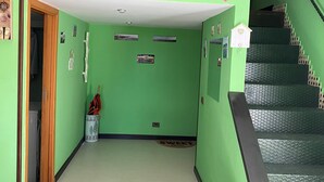 Um corredor com paredes verdes, uma escada e um banco.