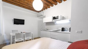 Habitación moderna con cama, escritorio, dos sillas, televisor, microondas y lavabo.