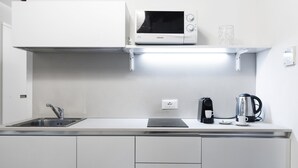 Una cocina moderna con microondas integrado, hervidor y cafetera.