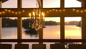 Una stanza con ampie finestre vista lago, un lampadario e poltrone in vimini.