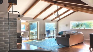 Un soggiorno spazioso con un'ampia finestra, un camino e un soffitto in legno.