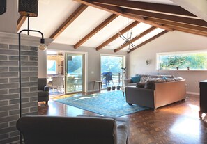 Relax in a spacious living area with a high ceiling, comfortable sofa, and cozy armchair, perfect for unwinding by the fireplace.